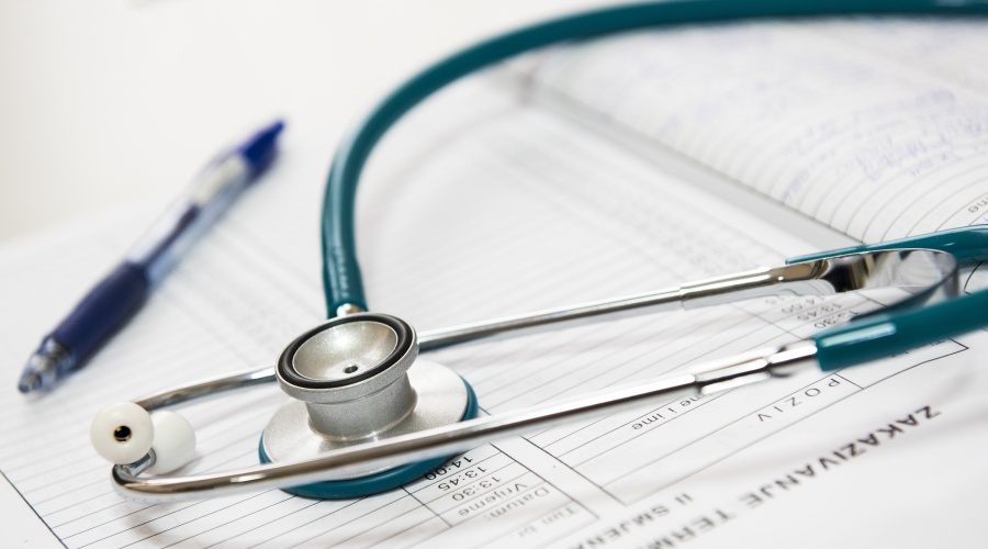 Stethoscope on top of some papers and a pen