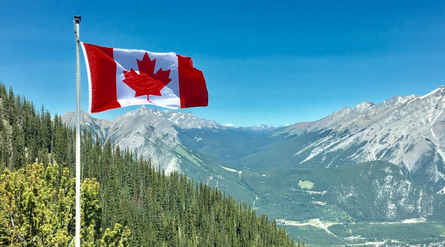 Canadian flag on pole against a mountain background