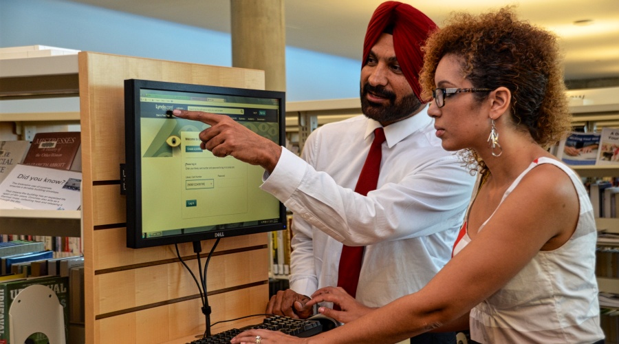 Man pointing out something on computer screen to a woman