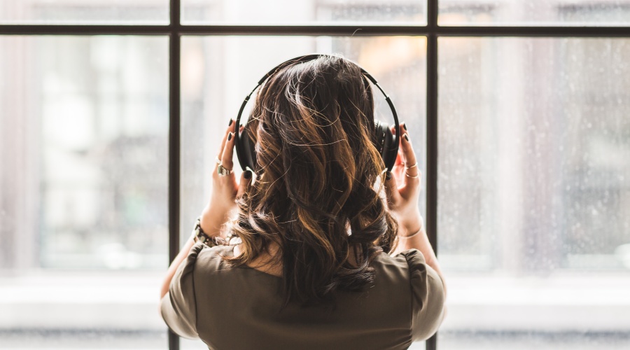Woman with headphones facing a large window