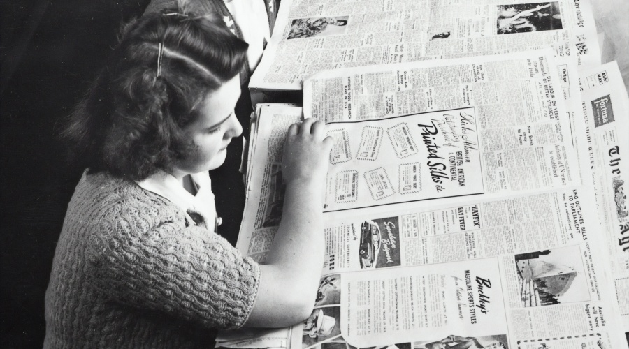 Vintage photograph of young woman reading newspaper