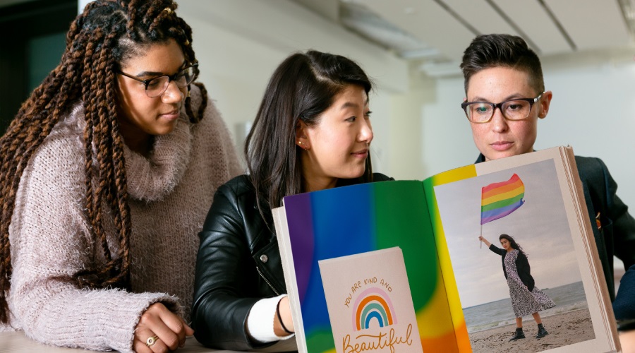Group of people around a book with a rainbow theme