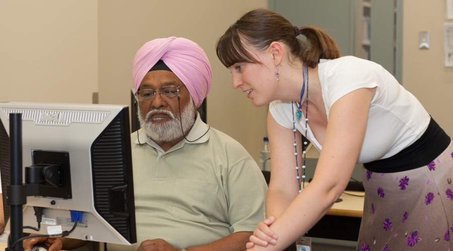 Woman helping man use the computer