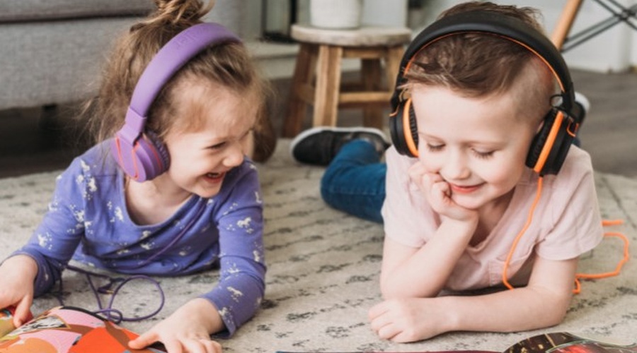 girl and boy lying on the floor with headphones and reading books