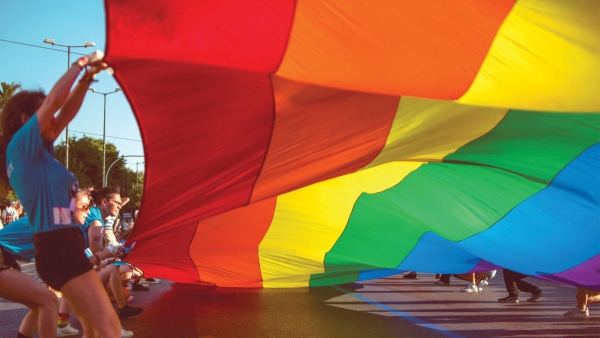 Group of people holding a very large rainbow flag