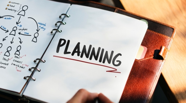 Hand with notebook with word planning written on a page