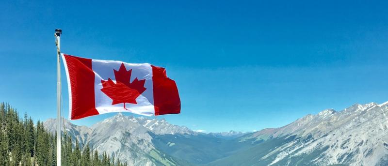 Canadian flag on pole against a mountain background