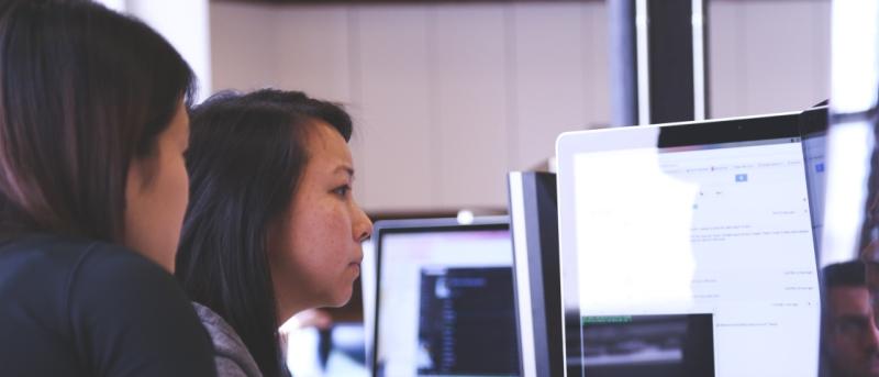Two people sitting around a computer