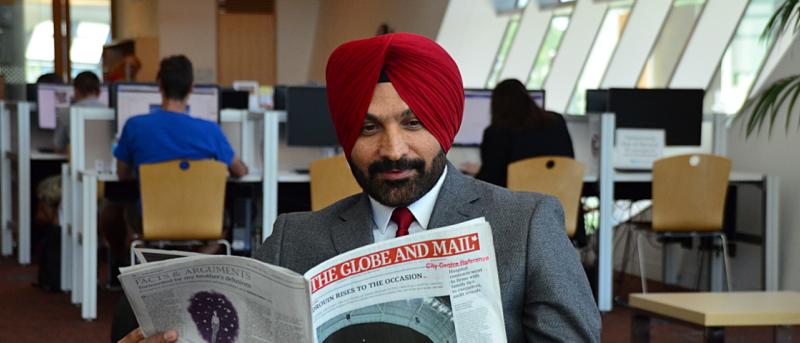 Man reading newspaper in library